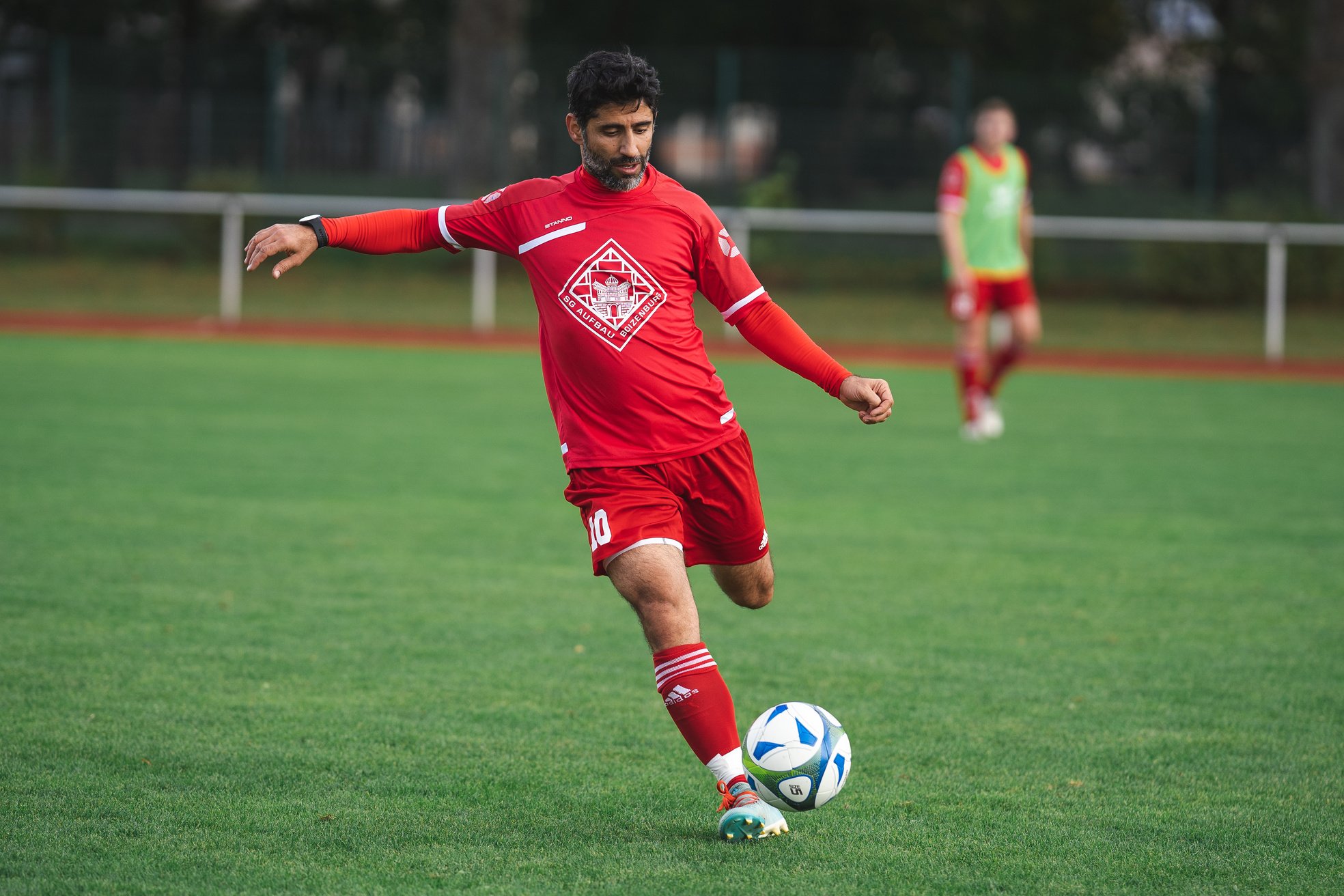 Man in Red Soccer Jersey Kicking Soccer Ball